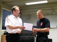 Herr Hartl überreicht das Gratulationsschreiben des Direktors der Feuerwehr Köln an Thomas Reiter.